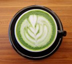 A mug of matcha tea latte with "Rosetta" latte art